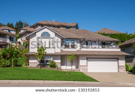Family house with big garage, trees in front, and concrete driveway