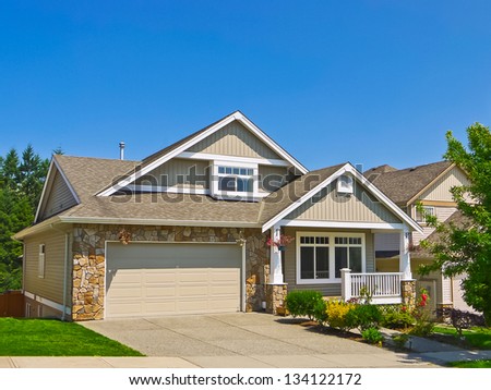 Average family house with concrete driveway to the garage. Blue sky background