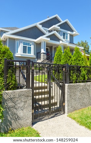 Front entrance of a nice house with concrete terrace and lattice fence in front. Gate and step way to terrace in front of the house.