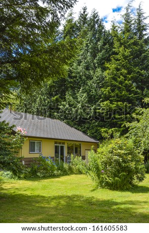 Frontage of a nice house among trees. Front side of a house on country side in British Columbia, Canada.