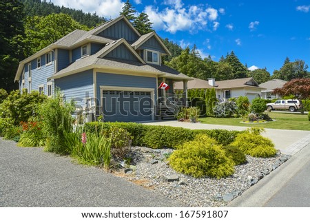 Family house with landscaping on the front and blue sky background. House with concrete driveway and wide double garage.