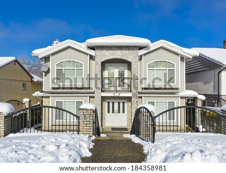 Luxury house with metal fence in front and blue sky background. Luxury family house on winter season with open entrance gate in front.