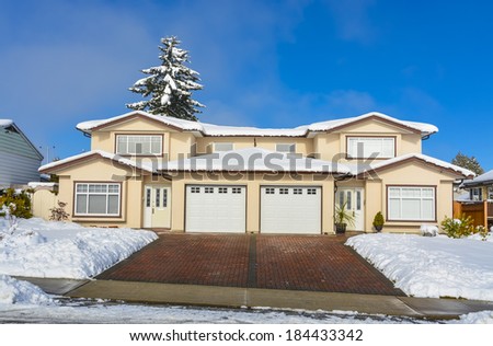 Renovated duplex house on winter season. Block paved driveway to the garages.