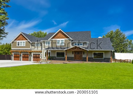 Brand new farmer\'s house in British Columbia, Canada. Huge family house with three garage door and blue sky background.