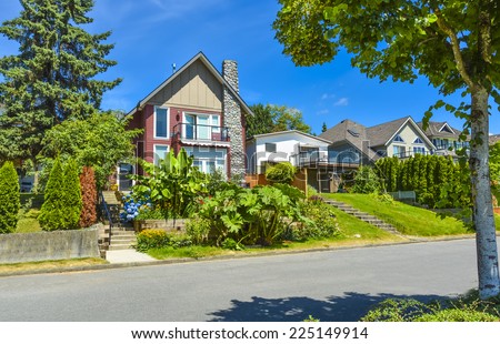 Beautiful suburban house over the street with landscaped terrace and blue sky background. Residential house at sunny day in British Columbia
