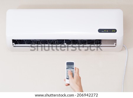 Air conditioner inside unit with man operating remote controller. / Air conditioner with remote controller