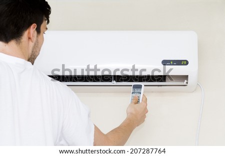 Men operating air conditioner with remote controller