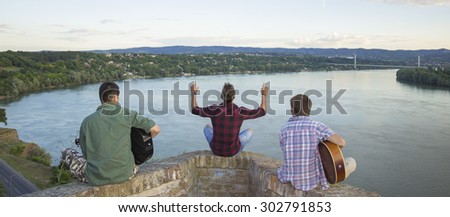 Three men band, sitting. Looking to river coast, from high above.