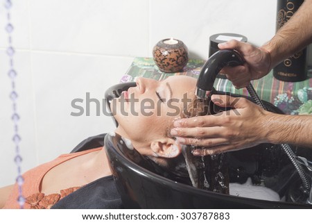 Hairdresser washing girls hair, pearls curtain in front.