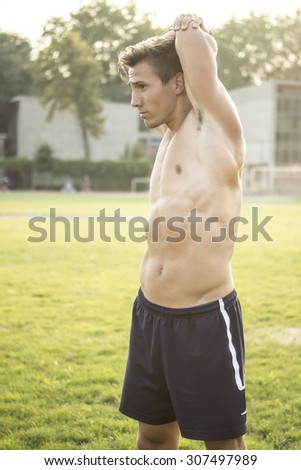 Muscular athlete stretching upper body.