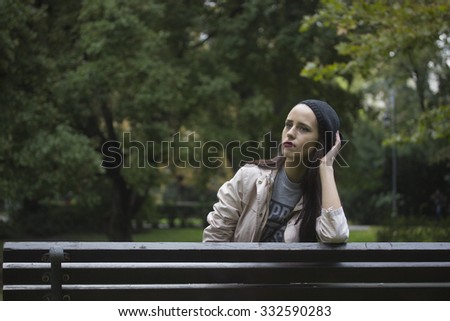 happy hipster girl in park, sitting in wood bench, strong horizontal lines