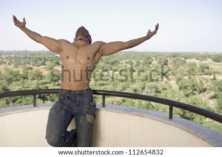 Man standing in the balcony with his arm outstretched