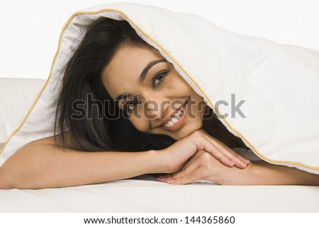 Portrait of a woman looking through a quilt