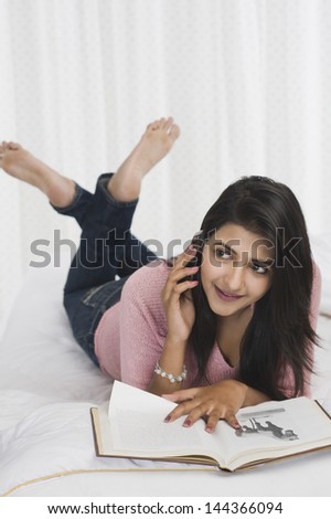 Woman talking on a mobile phone while reading a book