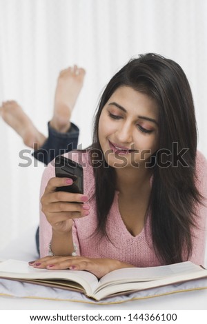 Woman using a mobile phone while reading a book