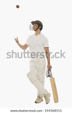 Cricket batsman tossing a cricket ball