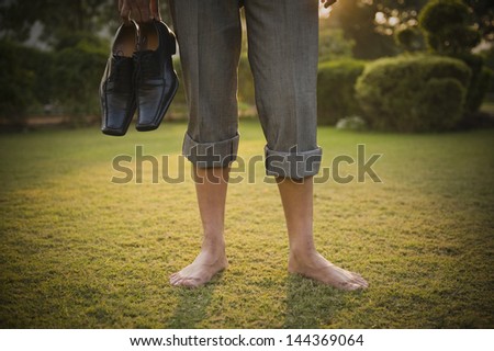 Low section view of a businessman holding shoes in a park