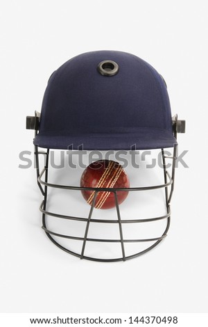 Close-up of a cricket ball under a cricket helmet