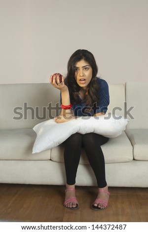 Woman holding an apple and watching tv