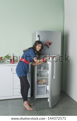 Portrait of a woman opening a refrigerator