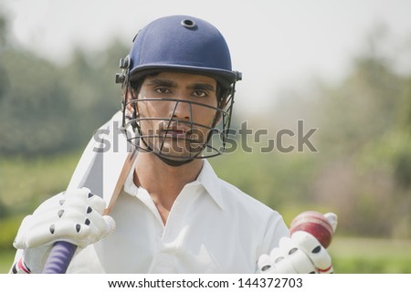 Cricket batsman holding a cricket bat with a cricket ball