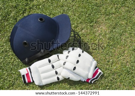 Cricket helmet and batting gloves in a field