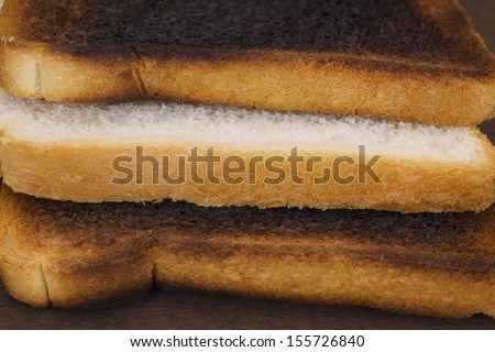 Slice of bread between two burnt toasts