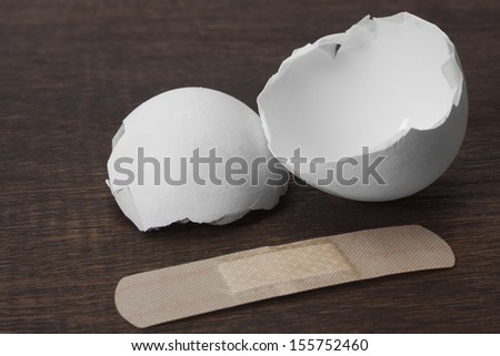 Close-up of a broken egg with an adhesive bandage