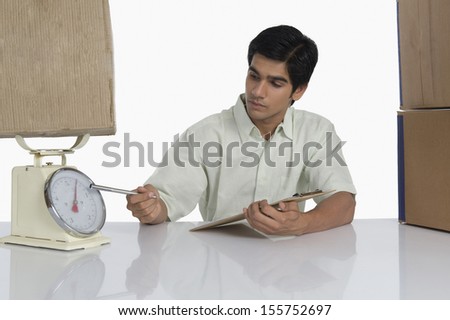 Warehouse worker weighing a package on a weight scale