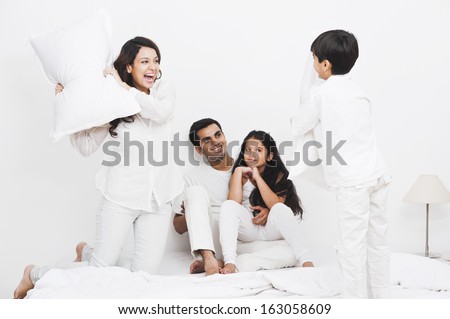 Happy family pillow fight on the bed