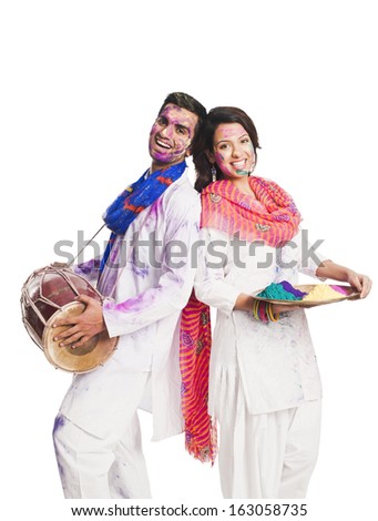 Couple celebrating Holi with colorful paints and a drum Couple celebrating Holi with colorful paints and a drum