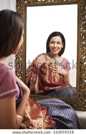 Reflection of a woman in mirror trying a sari on herself