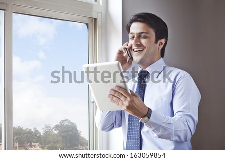 Businessman using digital tablet and talking on a cell phone