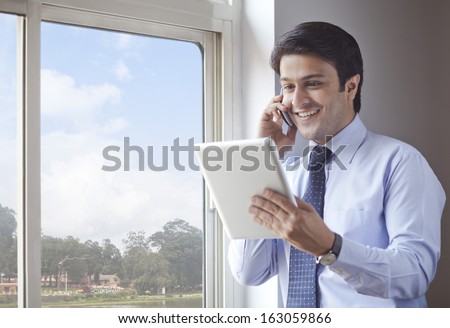 Businessman using digital tablet and talking on a cell phone