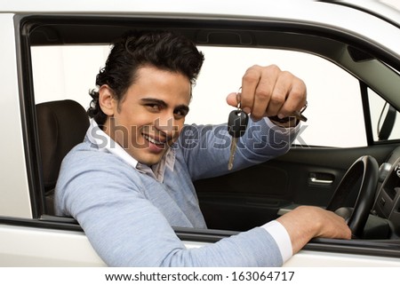 Smiling man sitting in a car and showing car key