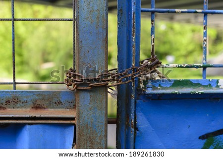 Close-up of blue rusty gates locked with chains