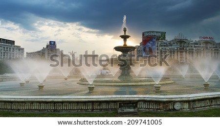 Bucharest, Romania - August 07, 2014: Unirii Square Water fountains splash in summer heat at dawn. Water fountains in center of Bucharest, Unirii area with People\'s House in background in dawn light
