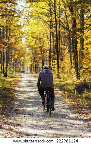 Old man riding a classic bicycle in autumn forest