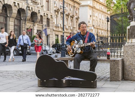 BUCHAREST, ROMANIA - MAY 29, 2015: Street musician playing a quitar to earn some money, in the oldtown of Bucharest, Romania