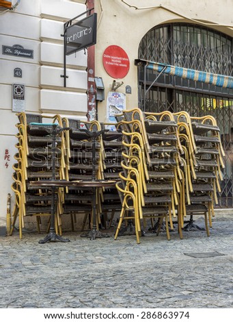 BUCHAREST, ROMANIA - SEPTEMBER 01, 2014 : Stack of chairs on Lipscani street in downtown of Bucharest, near a warning sign about buildings resistant to earthquakes