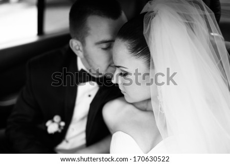 Loving newlywed bride and bridegroom in car