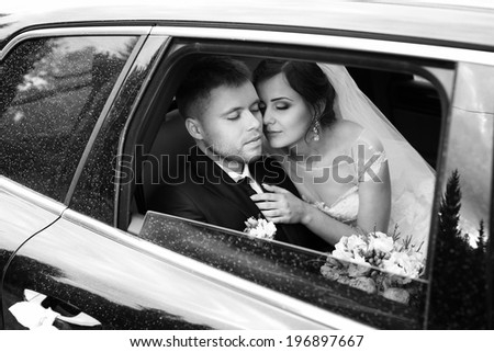 Loving newlywed bride and bridegroom in car