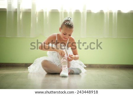 A little adorable young ballerina in white ballet dress tutu is