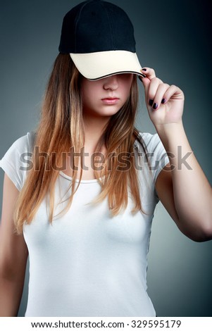 Portrait of young female  in white t-shirt  in a cap on dark background