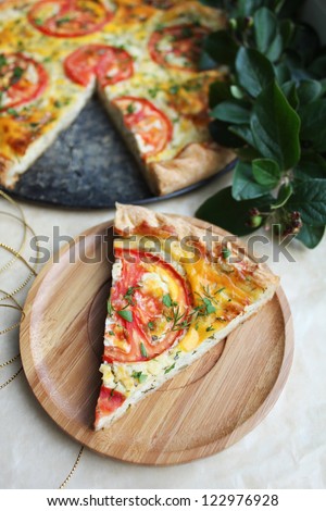 Puff pastry pie with curd cheese filling, tomatoes slices, cheese and chopped fresh herbs