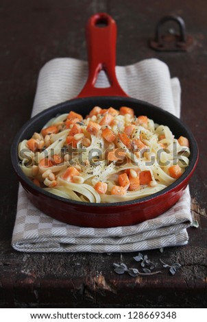 Cooked fettuccine pasta with roasted salmon, toasted pine nuts and cream sauce in a pan ready to serve