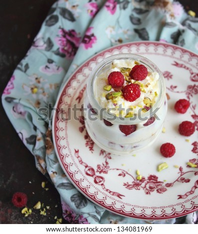 Whipped ice cream dessert with white chocolate, fresh raspberry and chopped pistachios in a jar