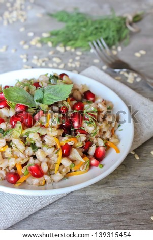 Portion of warm pearl barley salad with carrot and pomegranate seeds in a plate