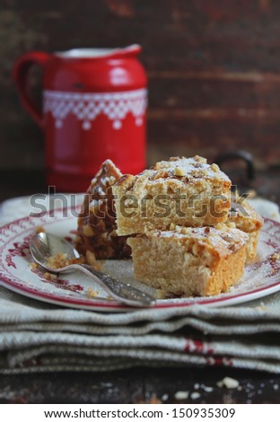 Pieces of nutmeg cake with icing sugar, chopped walnuts and maple syrup or honey drizzle on a dessert plate
