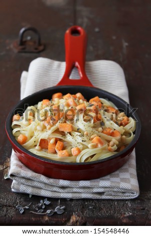 Homemade wheat pasta or noodles with roasted salmon, cream sauce, cheese and thyme in a pan